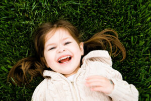 A child laughing as she lays on some grass