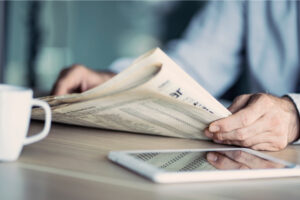 A man reading a newspaper at a table.