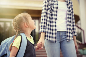 A mother and daughter holding hands as they walk to school. 