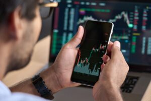 A man looking at a graph showing stock market performance on his phone.