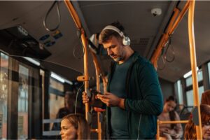 A man travelling on a bus with headphones on.