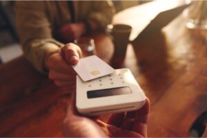 A person using their debit card to pay in a café.