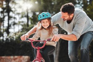 A father teaching his daughter to ride a bike.