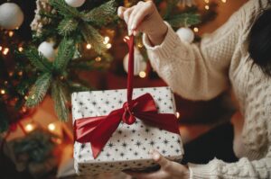 A woman untying a ribbon on a Christmas present.