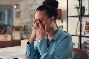 A woman sitting at a desk and looking stressed.
