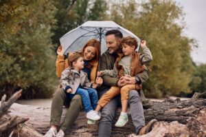 A young family sheltering under an umbrella and smiling